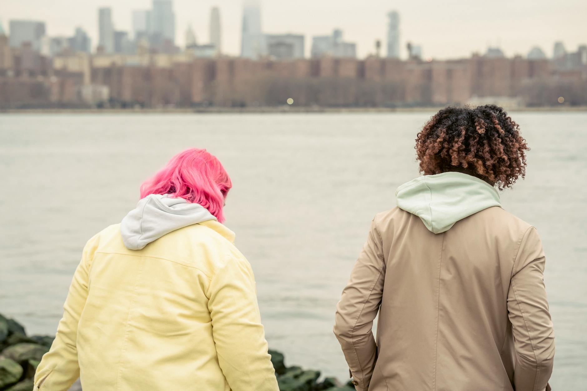 Grupa młodych ludzi nad rzeką z widokiem na nowoczesne budynki