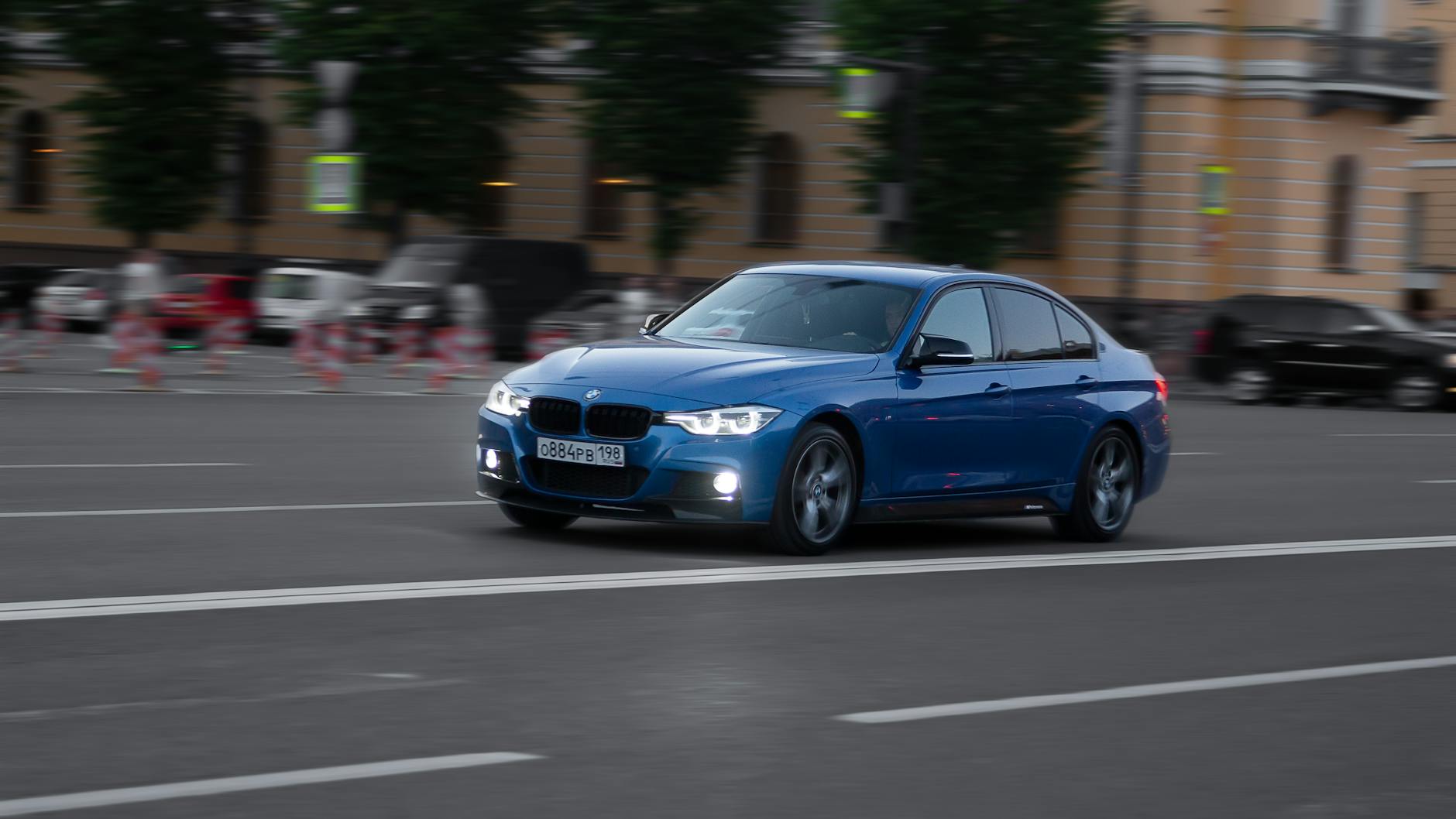 Niebieski samochód jedzie szybko ulicą wśród wieżowców megamiasta