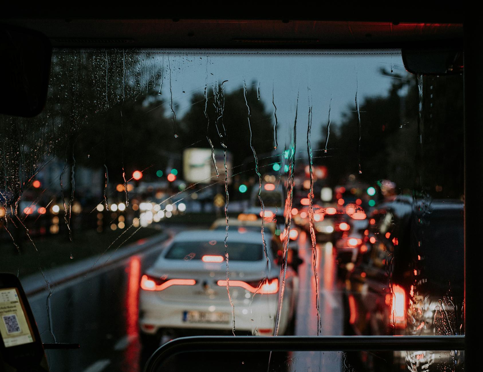 Nocny ruch uliczny widziany przez mokrą od deszczu szybę samochodu