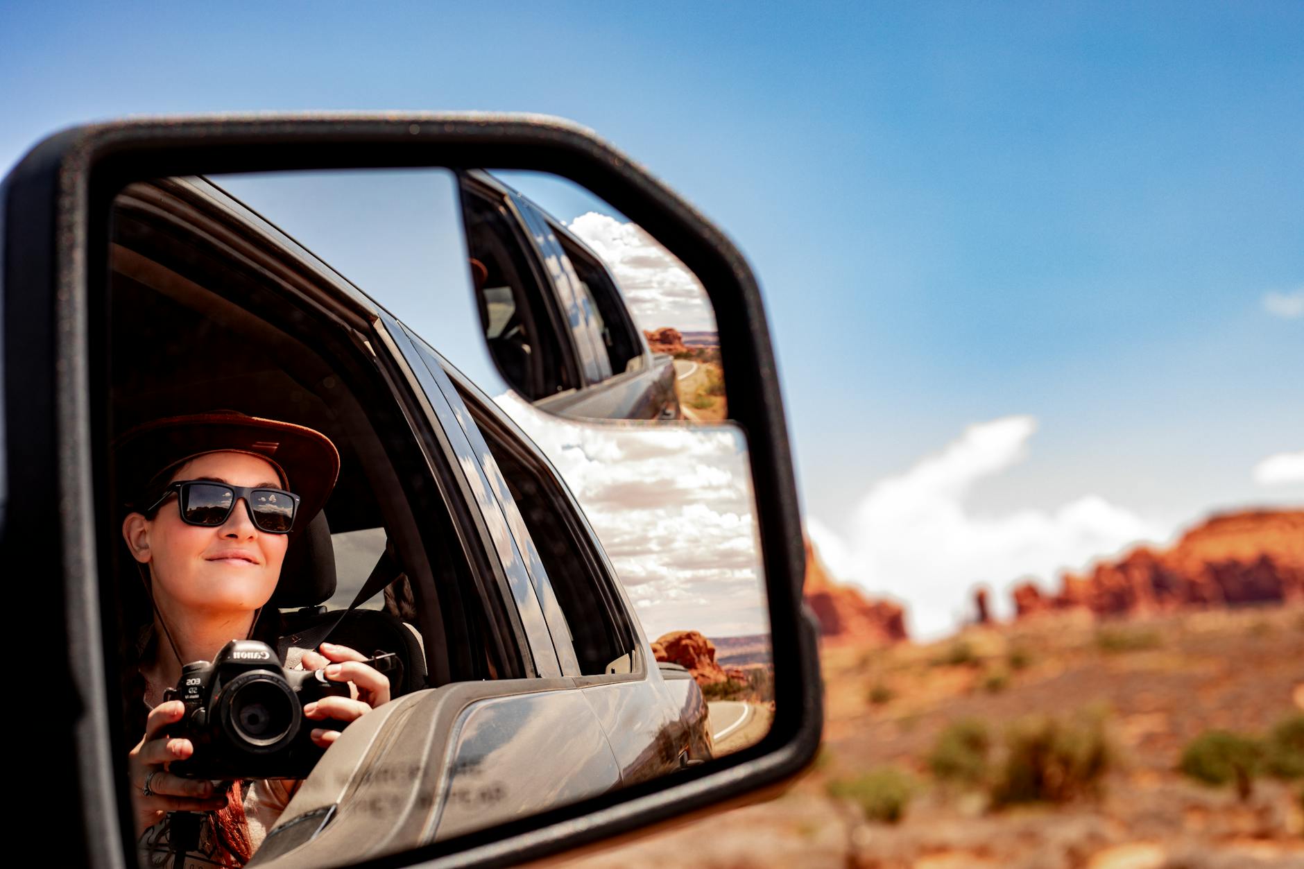 Odbicie fotografa w lusterku samochodu z pustynnym krajobrazem Utah