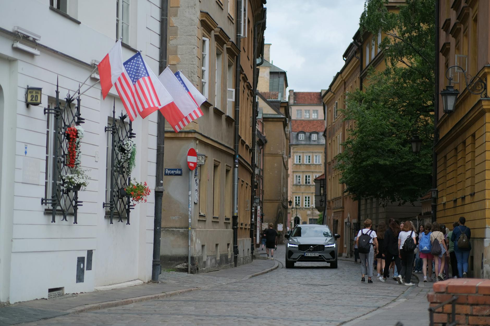 Ulica w Europie z flagami Polski i USA oraz przechodniami