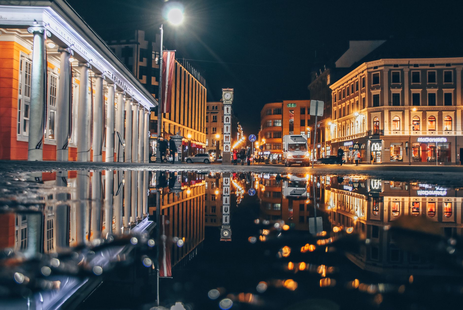 Nocny widok architektury Rygi odbitej w kałuży